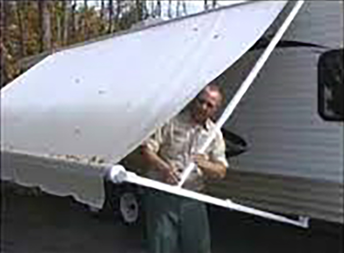 Man putting up manual RV awning.